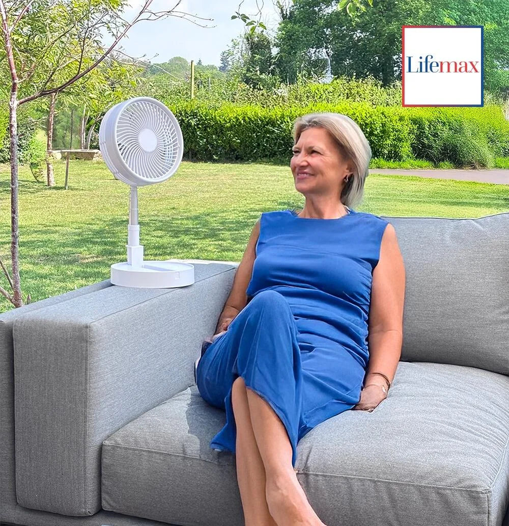 Woman in a blue dress sitting on a gray couch with a white fan and greenery in the background, featuring the Lifemax brand.