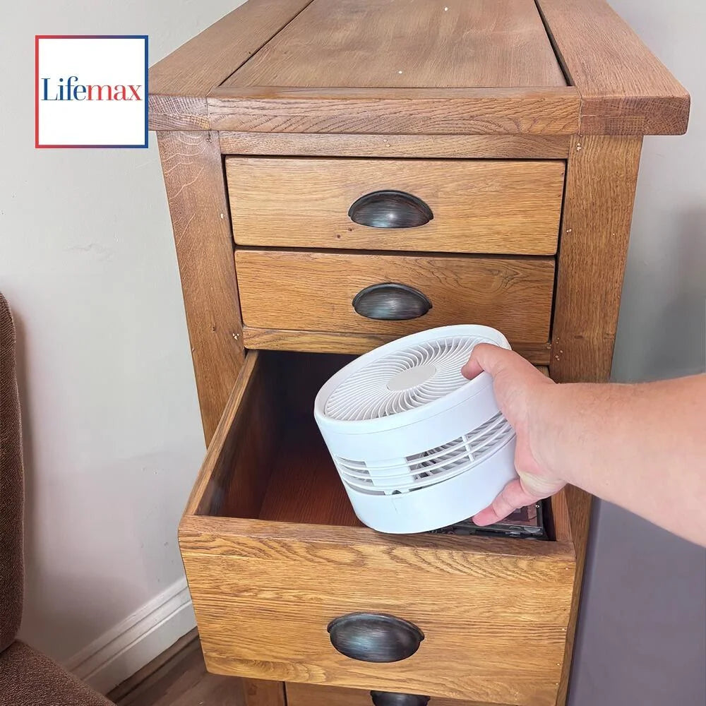 Hand placing a white air purifier into a wooden drawer.